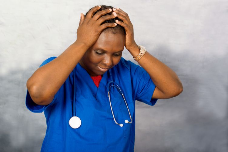 a young nurse standing with stethoscope at the neck and catches her head.